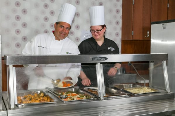 Chefs serving food in the dining area of a facility