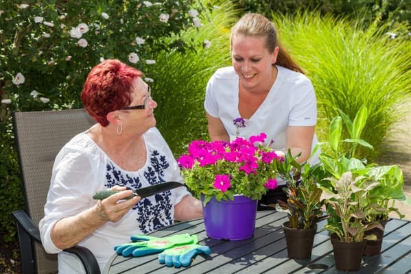 Resident and staff member gardening together outdoors