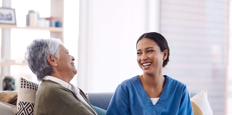 Resident and caregiver laughing together in a cozy setting