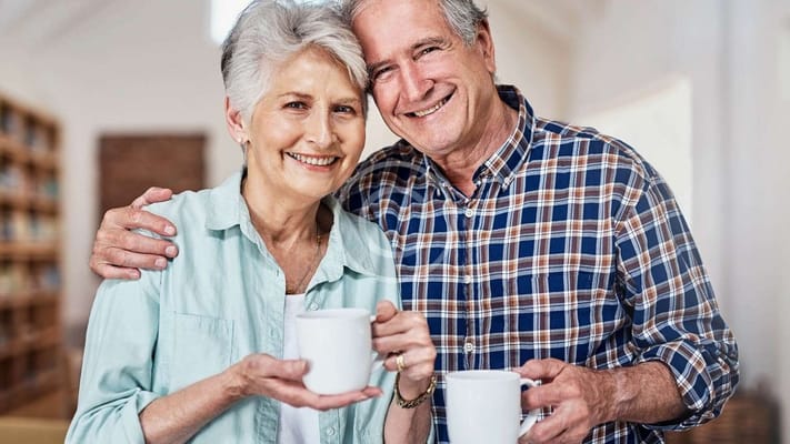 Smiling senior couple holding coffee mugs in a cozy setting