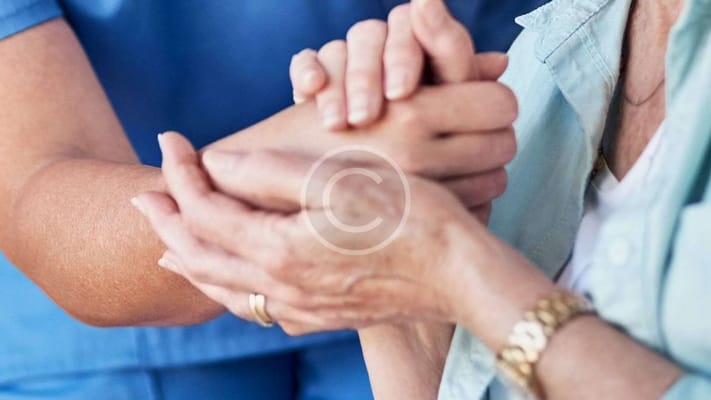 A caregiver holding the hands of a senior resident