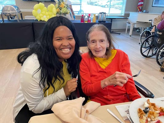 Resident enjoying a meal with staff member