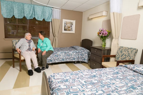 A resident and staff member chatting in a cozy room