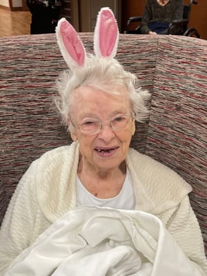 Elderly woman wearing bunny ears in a cozy armchair