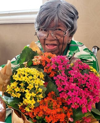 Resident smiling with a colorful bouquet of flowers
