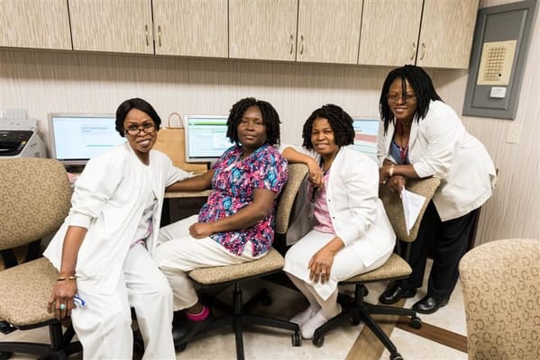 Four staff members smiling in an office setting