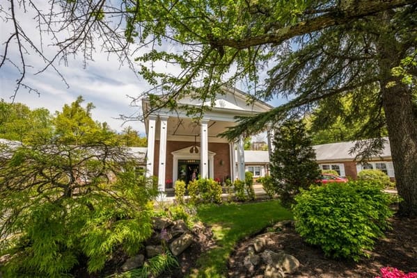 Front entrance of a senior living facility surrounded by greenery