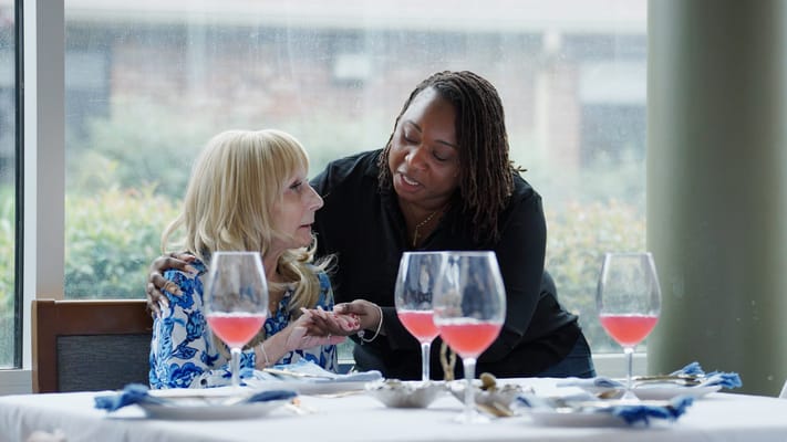 Staff member assisting a resident at a dining table