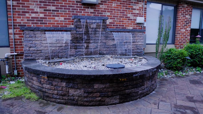 A decorative outdoor water fountain surrounded by plants