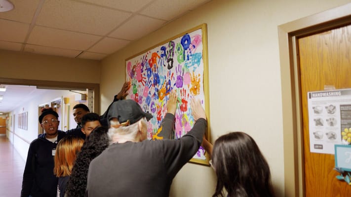 Residents and staff interacting with a colorful mural