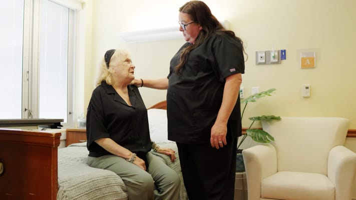 Staff member interacting with a resident in a cozy bedroom