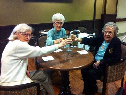 Three elderly women enjoying drinks at a table