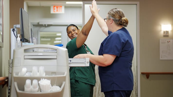 Two staff members high-fiving in a hallway
