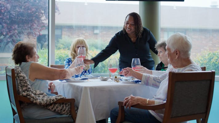 Residents and staff enjoying drinks at a dining table
