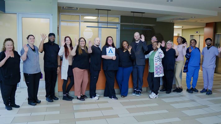 Staff members posing and waving in the facility lobby