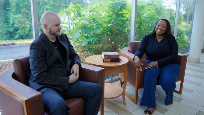 Two residents engaging in conversation in a sunny lounge