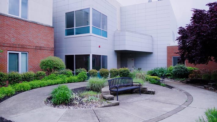 A landscaped outdoor space with seating near the facility entrance