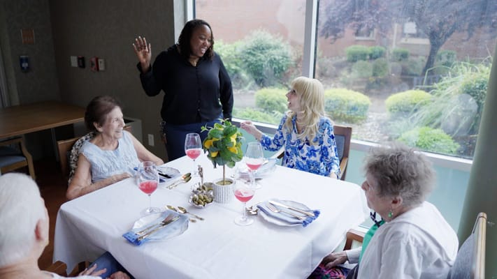 Residents enjoying a meal with staff in a dining area