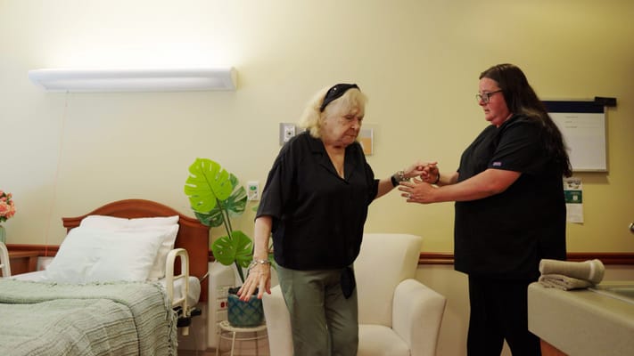 Staff assisting a resident in a facility room