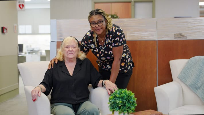 Resident and staff member smiling in a cozy lounge area