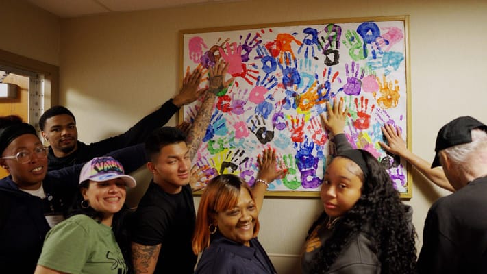 Residents and staff showcasing a colorful handprint mural