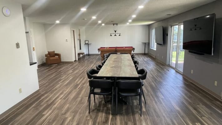 Bright common area with a long table and pool table