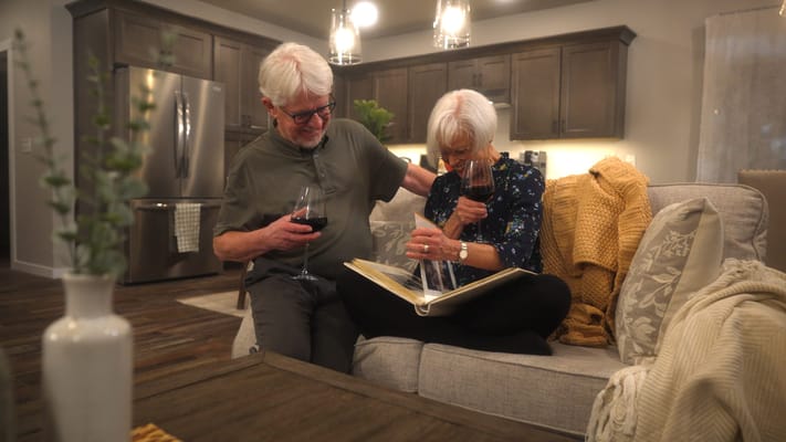A couple enjoying wine and looking at a photo album in a cozy living room