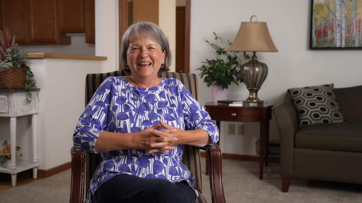 Smiling resident seated in a cozy living area