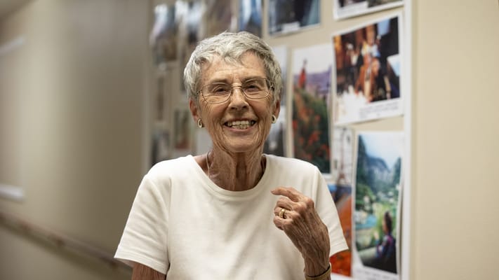 A resident smiling in a hallway with photos