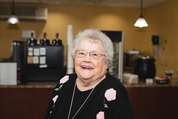 A senior woman smiling in a cozy cafe setting