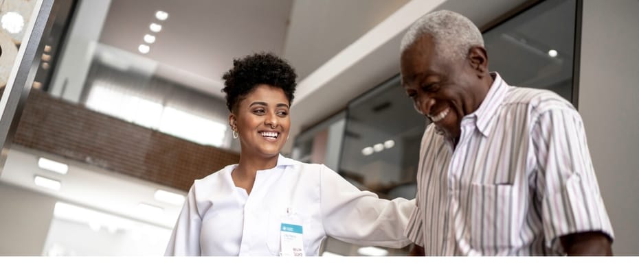 Staff assisting a resident in a bright hallway