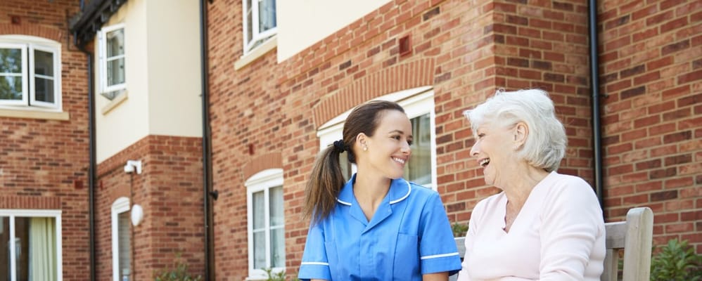 Caregiver laughing with resident in an outdoor space