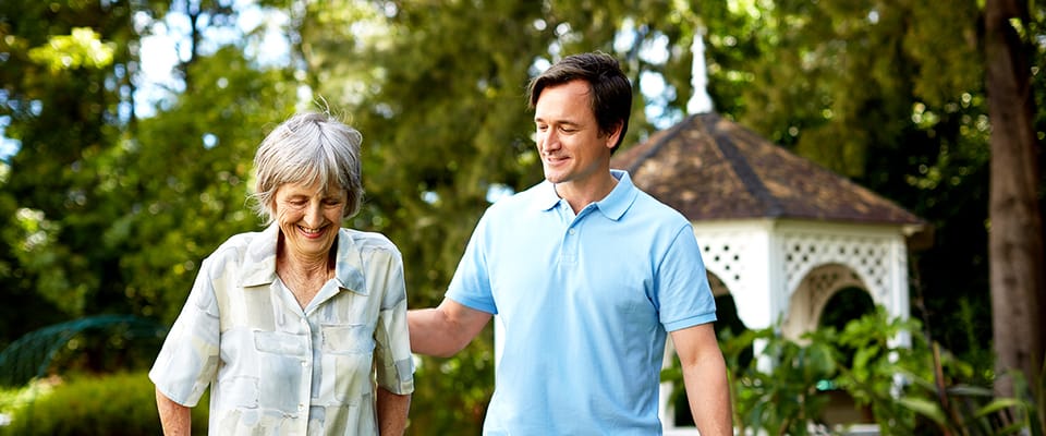 A senior woman walking outside with a caregiver