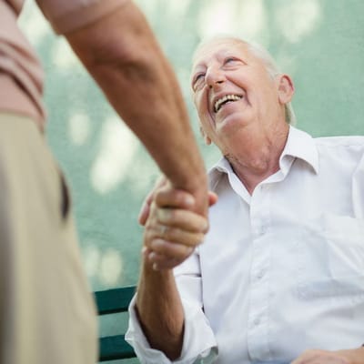 Resident greeting staff with a handshake in a garden