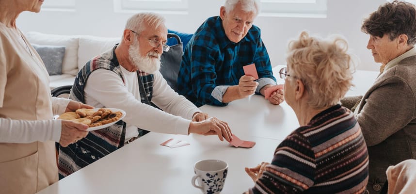 Residents playing cards together in a bright room