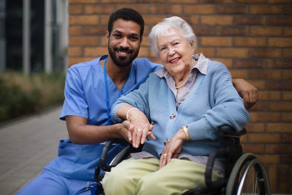 Caregiver and resident smiling in outdoor setting