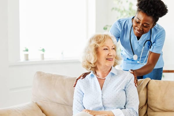 Caregiver assisting a smiling resident in a cozy setting