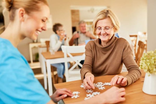 Resident and staff enjoying a puzzle activity in the common area