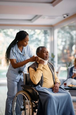 Nurse assisting a resident in a wheelchair in a bright room