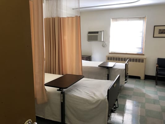 Two empty hospital beds in a resident room