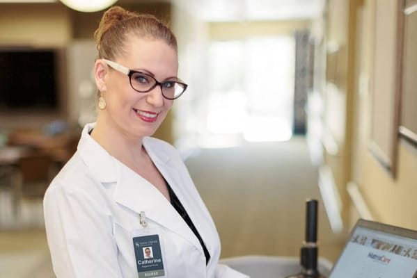 Nurse smiling in a facility corridor