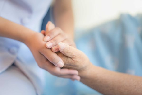A caregiver holding the hand of a resident