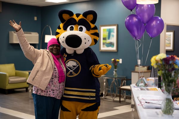 Resident and mascot celebrating in the lobby