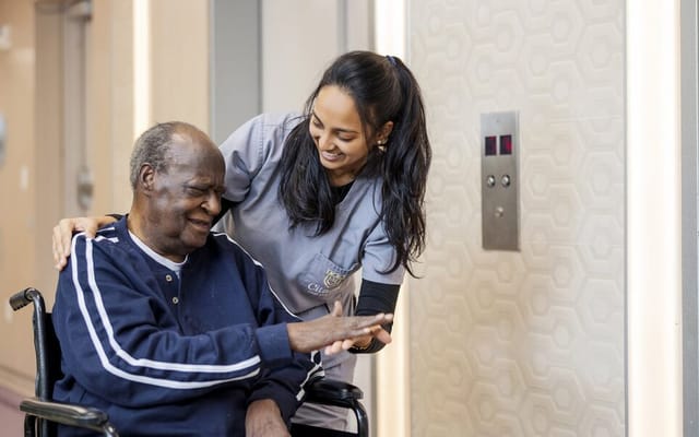 A caregiver interacting warmly with a resident in a hallway