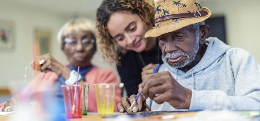 Residents engaged in an art activity with staff assistance
