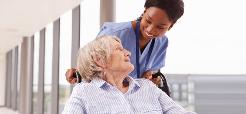 A caregiver smiling at a resident in a hallway