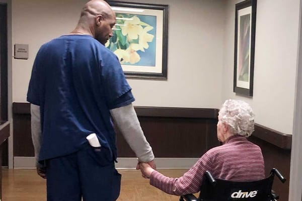 Staff member holding hands with a resident in a hallway