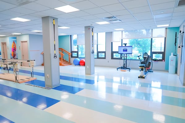 Bright therapy room with exercise equipment and windows