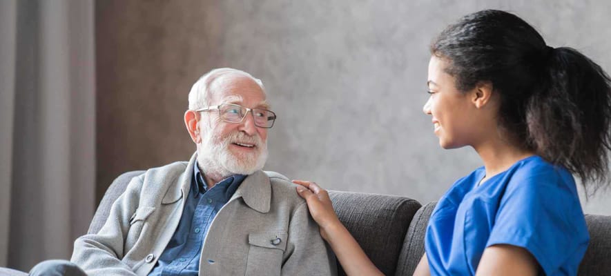 Senior man smiling with caregiver in friendly conversation