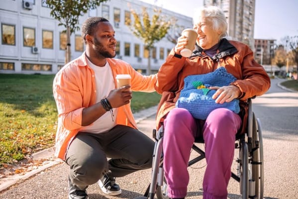 Resident enjoying coffee with staff in a garden